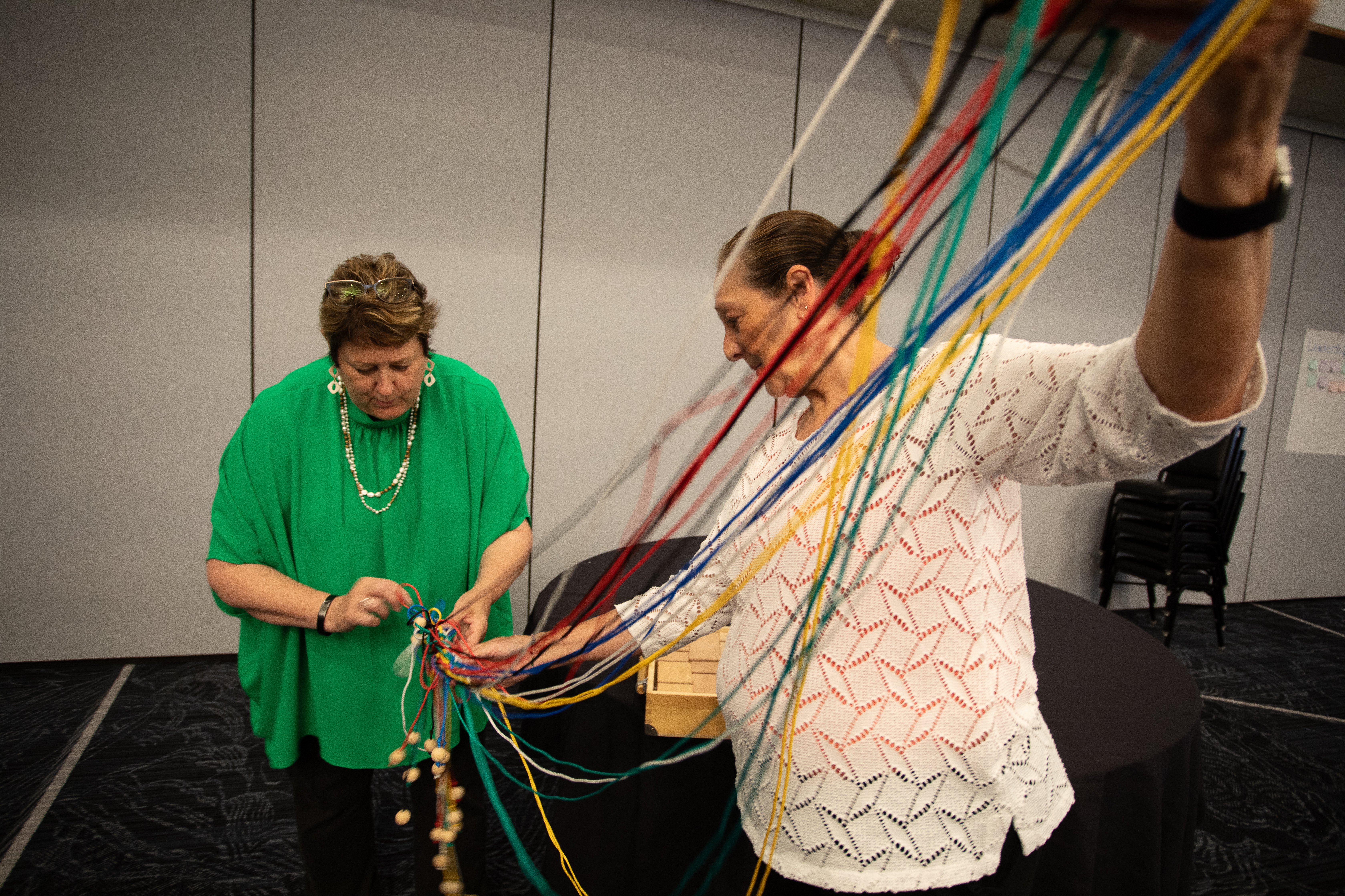 Jan Green and Nancy Rife work to untangle cords for a team-building exercise during Pathways | Award-Winning Talent Development Programs