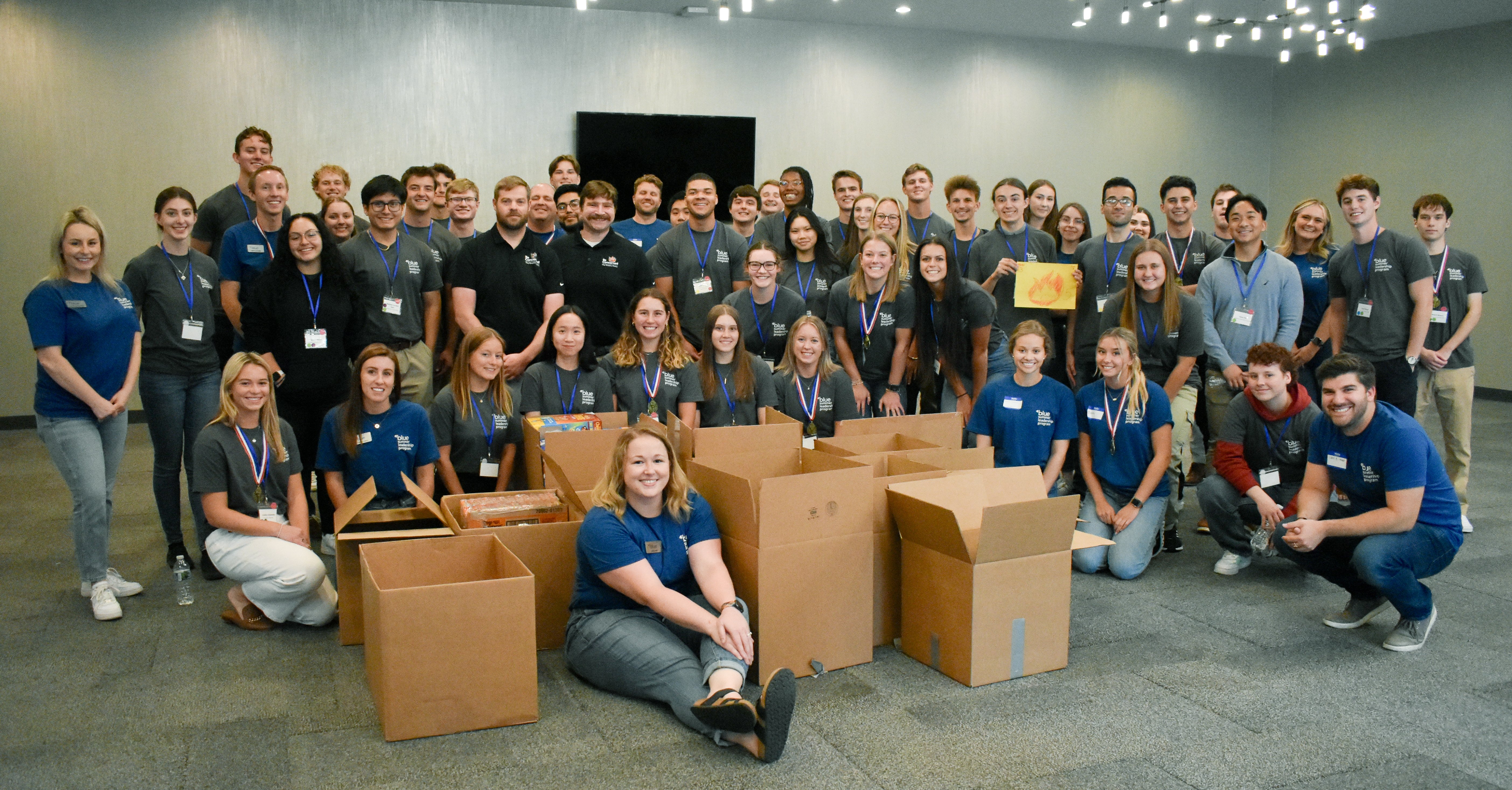 The Summer Leadership Program 2023 group smiling while standing besides boxes of food being donated to a Covington foodbank.