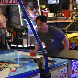 Student plays air hockey at Summer Leadership Program 2023 Networking event