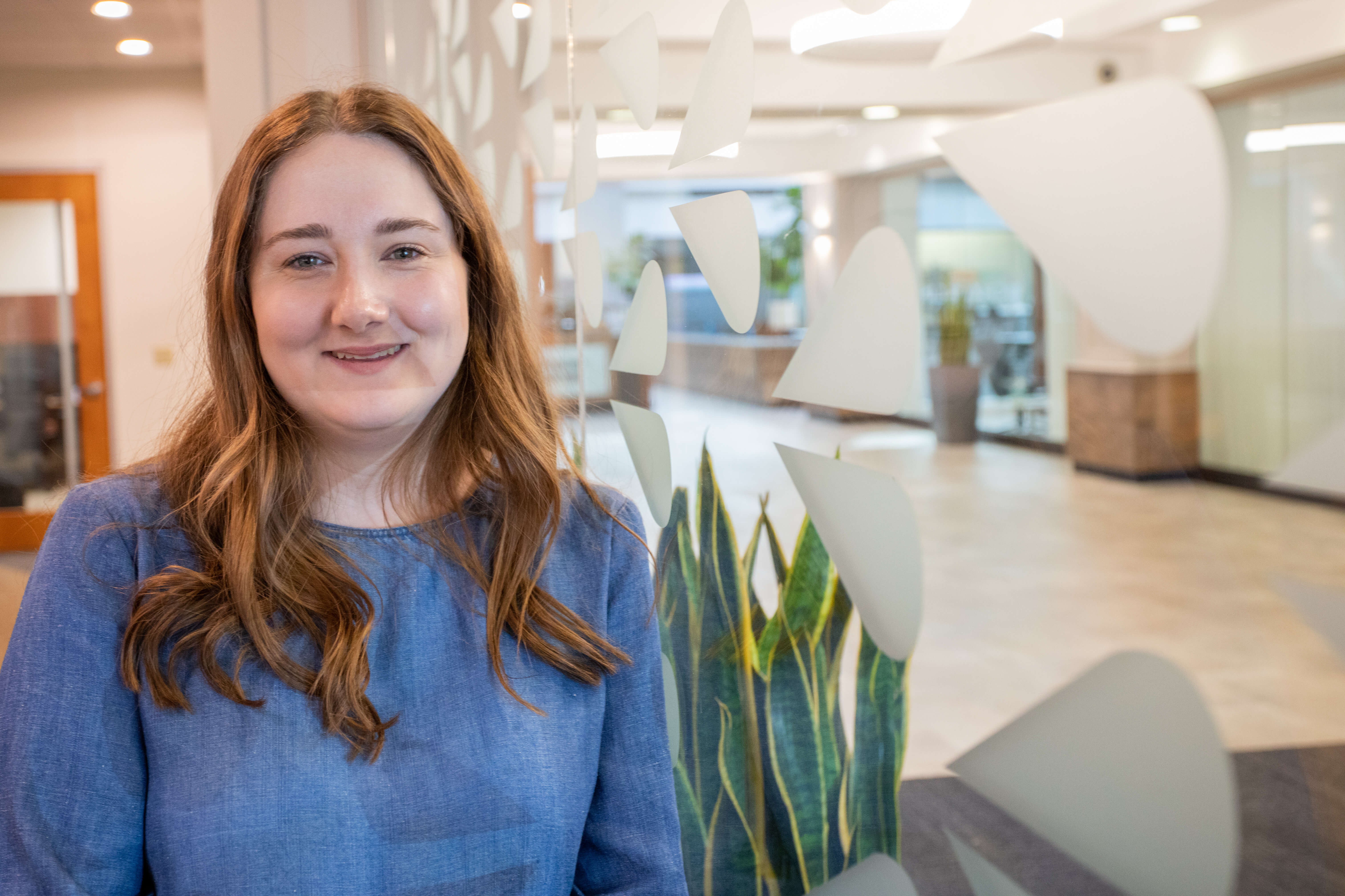 Intern standing in front of glass office wall