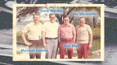 A vintage photo of Ron Blue and three other business partners posing for a photo at an outdoor company retreat
